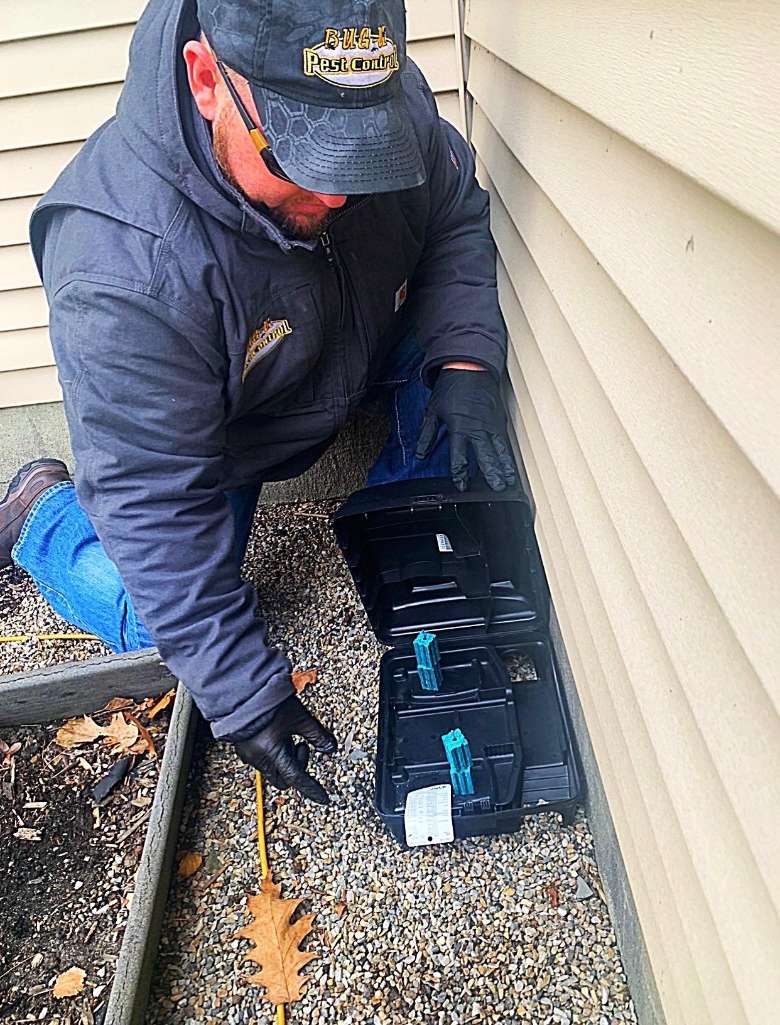 man kneeling on ground with small box of pest control rodent equipment