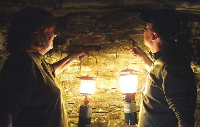 two people in a cave with lanterns