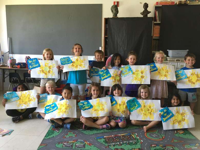 kids holding up paper with artwork on them