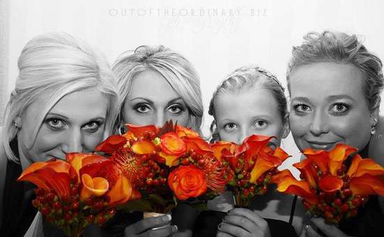 Girls in black and white looking out from behind bright orange flowers 