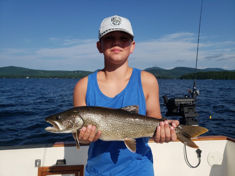 child in hat holding fish