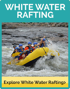 Rafters in blue helmets riding a yellow raft through the rapids