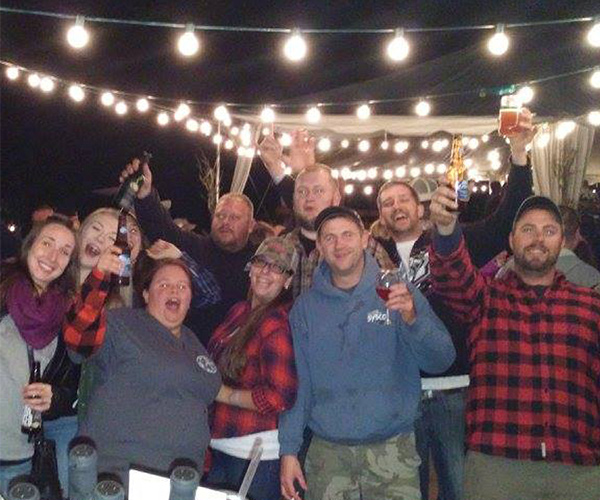 group of people in flannels with wine glasses and beers