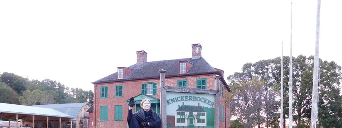woman in a period outfit standing in front of the knickerbocker mansion