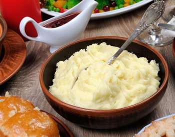 bowl of mashed potatoes, gravy and other dinner items surrounding it