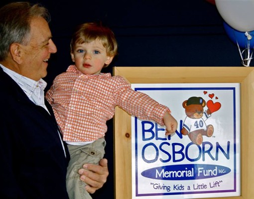man holding up little boy in front of Ben Osborn sign