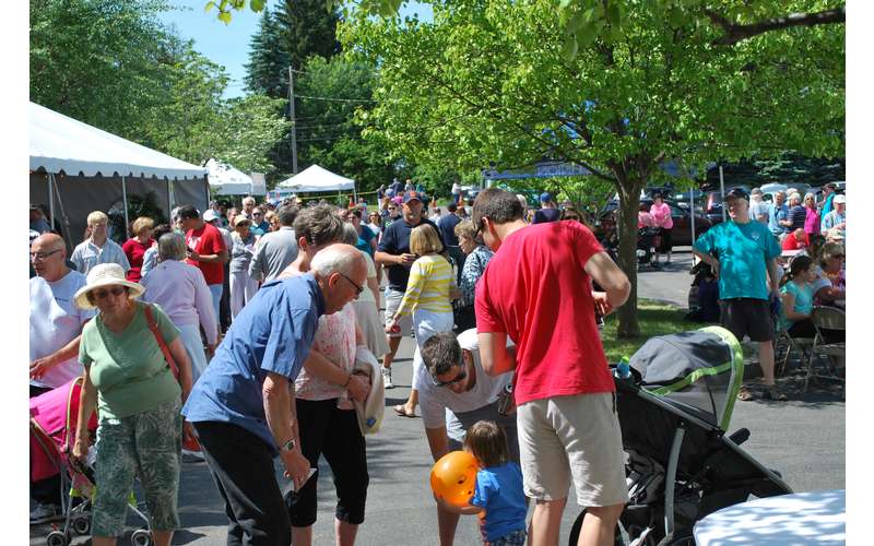 people outdoors at a festival with vendor tents