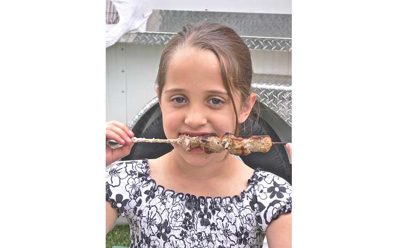 girl eating meat on stick