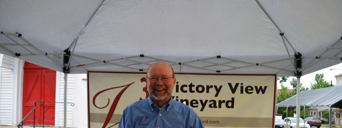 Man standing in front of Victory View Vineyard sign