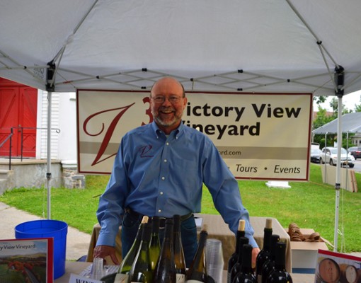 Man standing in front of Victory View Vineyard sign