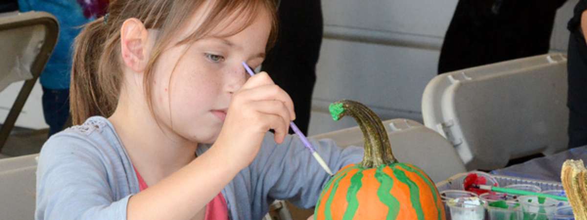 a little girl painting a pumpkin