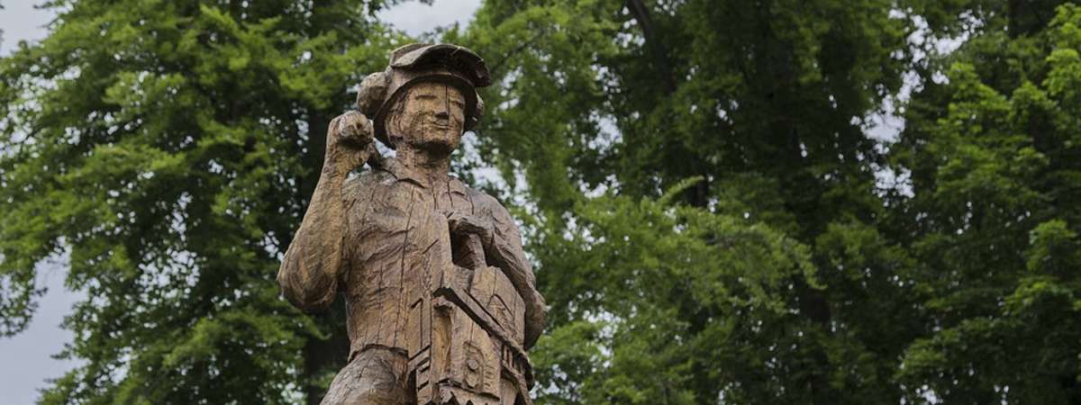 a lumberjack statue holding chainsaw made out of wood