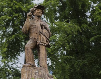 a lumberjack statue holding chainsaw made out of wood