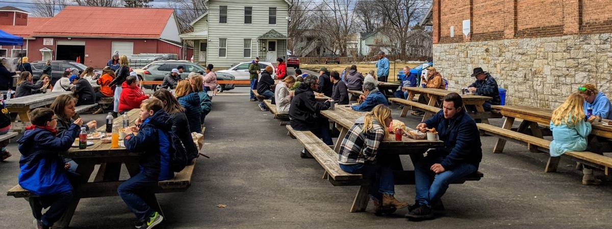 people eating at picnic tables outdoors