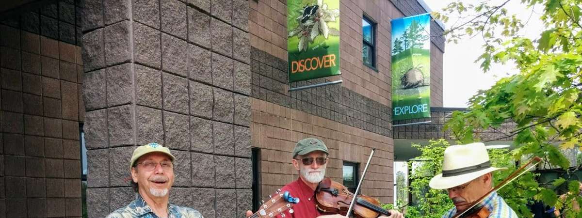 three musicians playing in front of the Discover Center