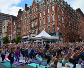 people doing yoga outdoors on a city street