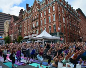 people doing yoga outdoors on a city street