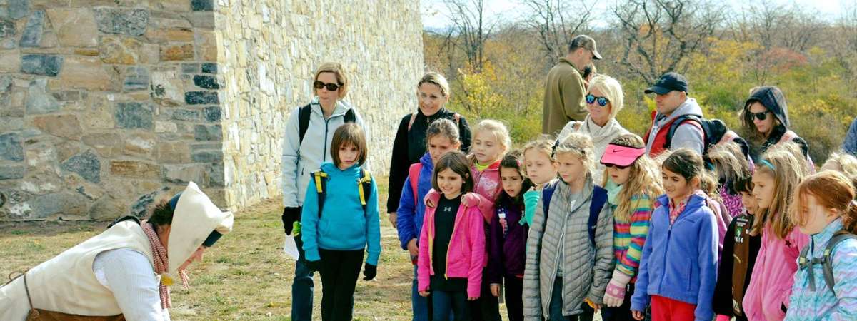 young girls watch reenactor at historic site
