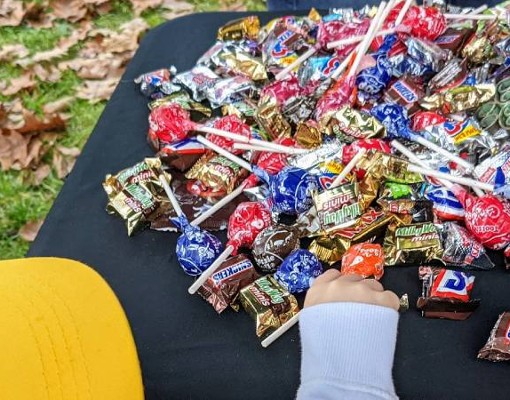 closeup of kid grabbing a lollipop off a table with a fake severed head