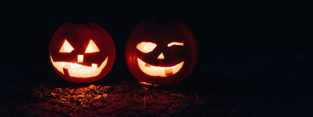 two lit up pumpkins next to eachother