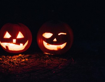 two lit up pumpkins next to eachother