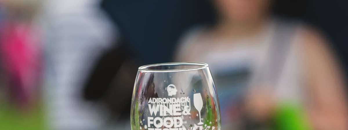 person holding an adirondack wine and food festival wine glass