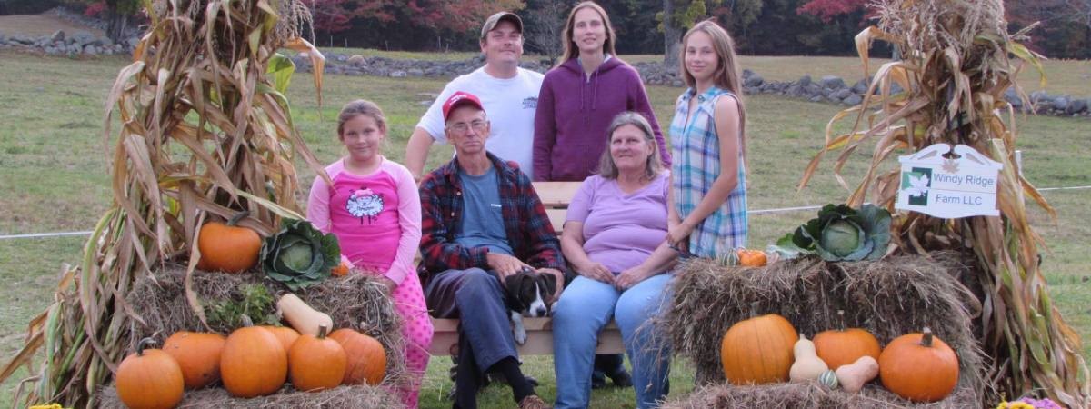 family poses by pumpkins and hay bales