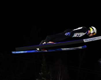 Ski Jumper flies across the sky on a winter night.