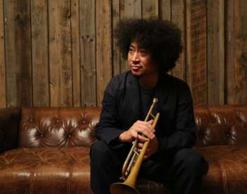 Takuya Kuroda sitting on a leather couch with a trumpet