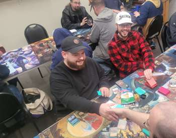 group of guys sitting at a table playing board games from the Dominaria Remastered Release