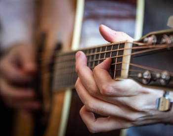close up of hands playing a guitar