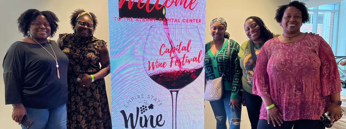 women standing by a wine sign.