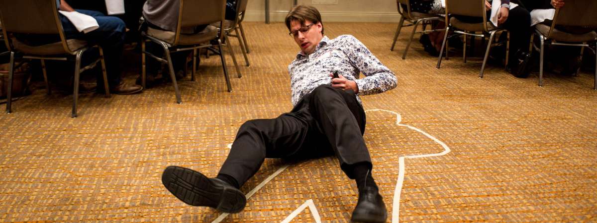 man laying on ground with crime scene tape around him