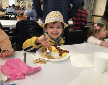 kid in easter hat eats breakfast
