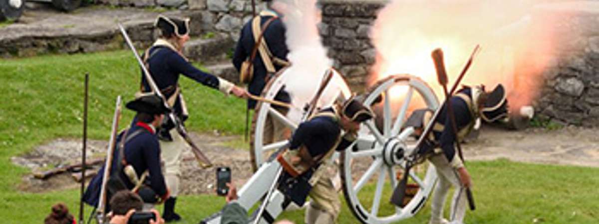 soldiers firing a cannon while a group of people watch