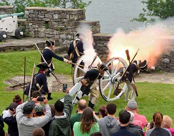 soldiers firing a cannon while a group of people watch