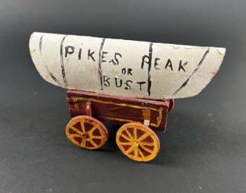 small sculpture of a covered wagon with text pikes peak or bust