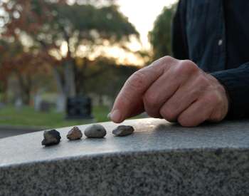 closeup of a hand on small rocks on a grave