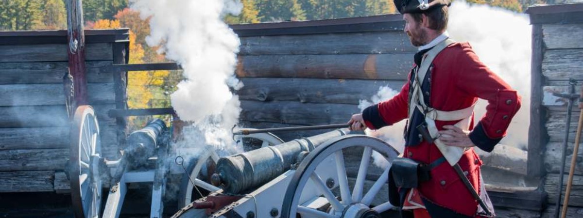 man in old soldier outfit lighting a canon