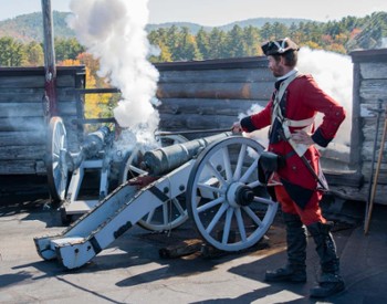 man in old soldier outfit lighting a canon
