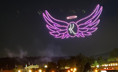 Purple and blue colored drones in the sky shaped as the Kelly's Angels logo