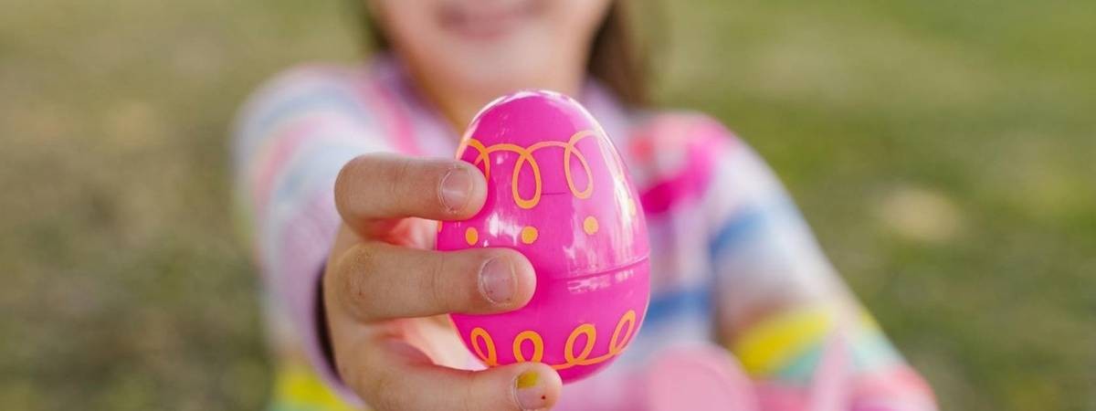 little girl holds up pink easter egg