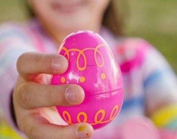 little girl holds up pink easter egg