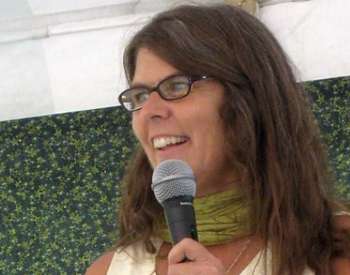 woman with brown hair and glasses holding up a microphone