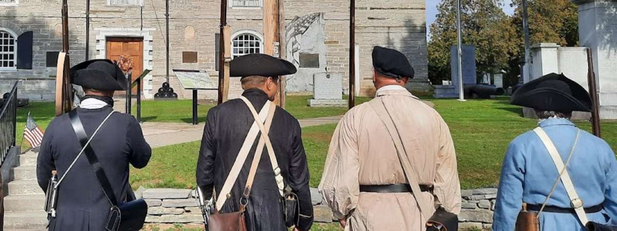 Four 18th century militia members facing the Old Stone Fort