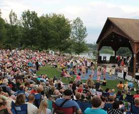 Large crowd in a park in front a pavilion style stage