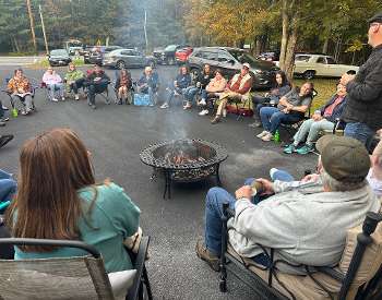 Large group of people sitting around campfire
