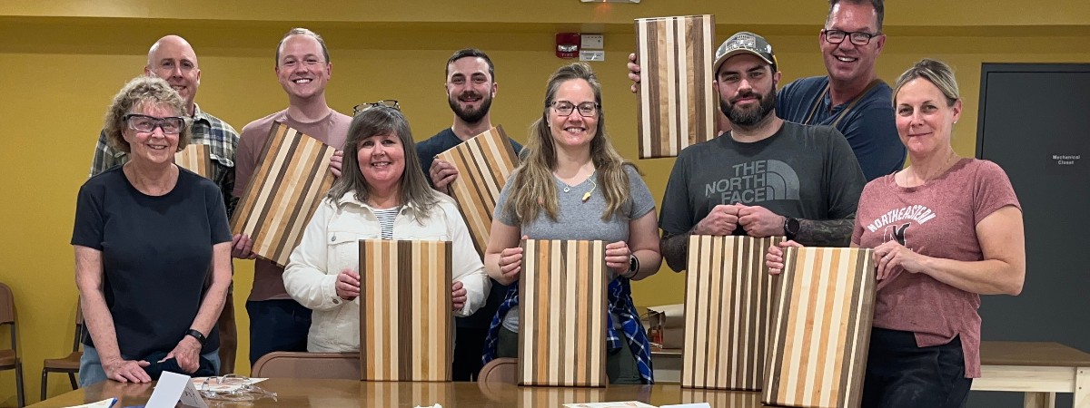 a group of people hold up cutting boards
