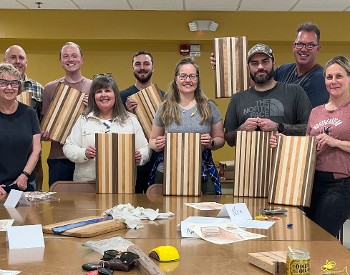 a group of people hold up cutting boards