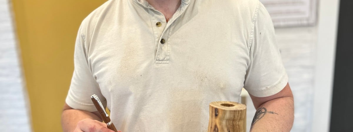 student holds finished candlestick and pen